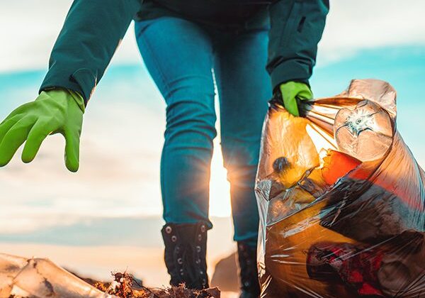 Person cleaning up trash on beach.
