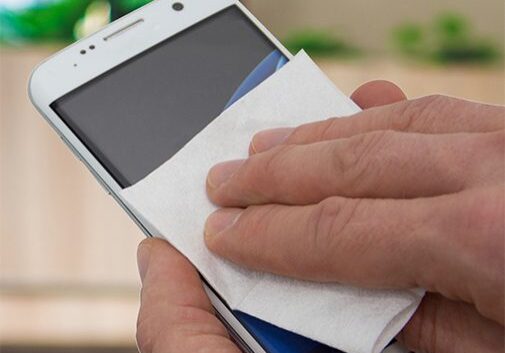 Cleaning phone screen with wipe.